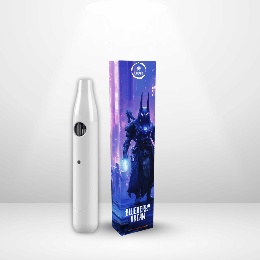 En elegant vit Faraoh THCB/THCHO Engångsvape 35% 1ml står bredvid en hög låda prydd med fantasikonst av en mörk pansargestalt och texten "BLUEBERRY DREAM". Den ljusa bakgrunden framhäver denna CCELL Vulkano-enhet.
