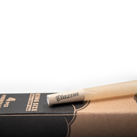 Närbild av en Partybolaget Premium 4st Pre-Rolled Joints, king size, vilande på en delvis synlig brun och svart förpackning med 4 st.