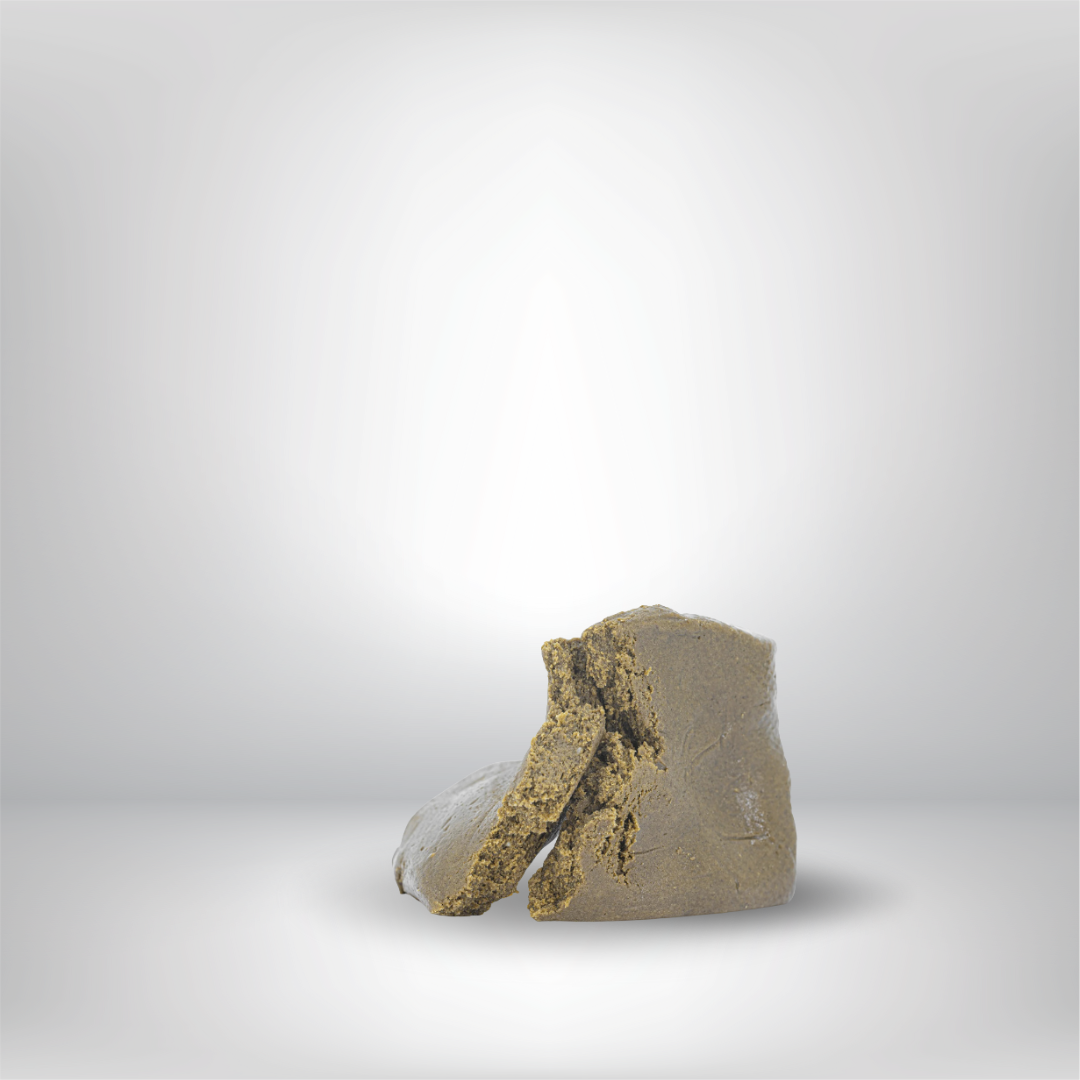 Närbild av två bitar brunaktigt, smuligt Partybolaget Dry Static THCA 5g 30% Hash på en slät, ljusgrå yta med en mjukt suddig, gråtonad bakgrund.