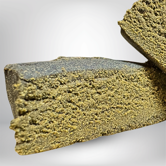 Närbild av två täta, smuliga bitar av Static Pollen THCA 5g 35% - Infused Hash by Partybolaget, staplade på en ljusgrå bakgrund - premium cannabinoidinnehåll garanterar kvalitet i varje detalj.