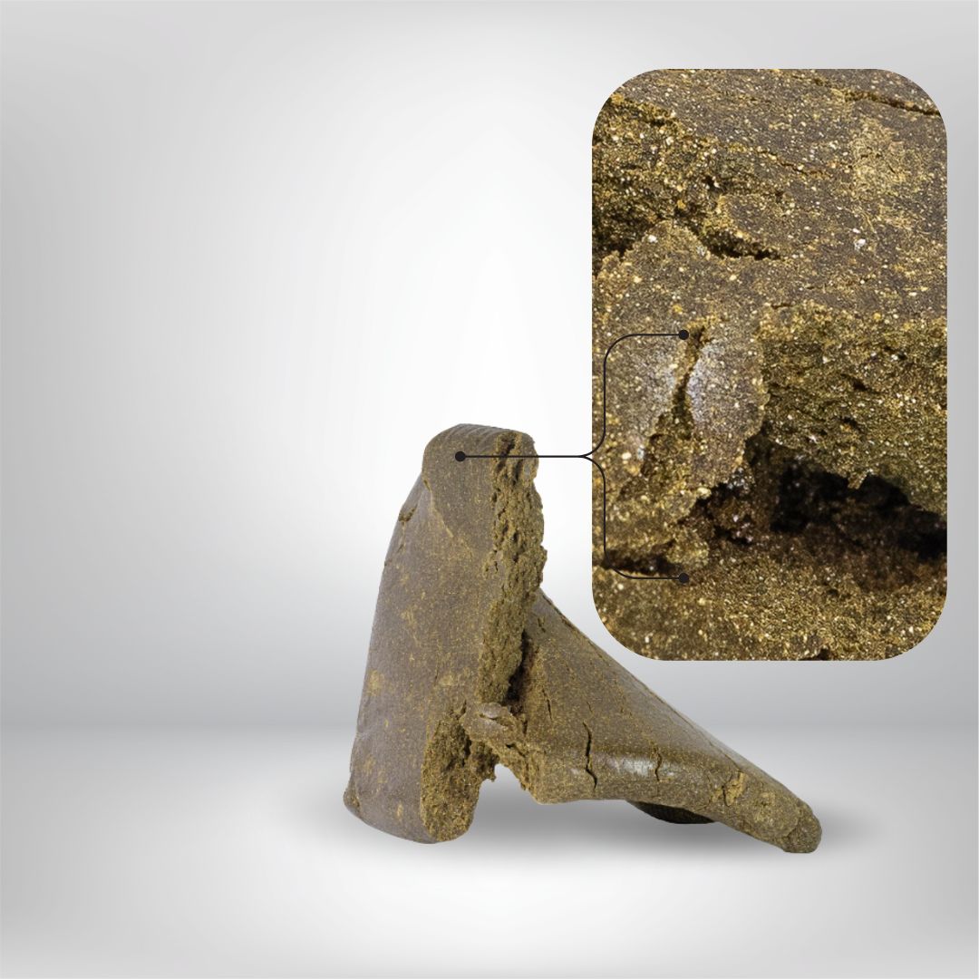 En bit av Partybolagets Dark Charas THCA 5g 31% Hash ligger på en ljus bakgrund, dess bruna, smuliga yta markeras; en infälld zoom visar dess granulära struktur, gnistrande partiklar och höga THCA-innehåll.